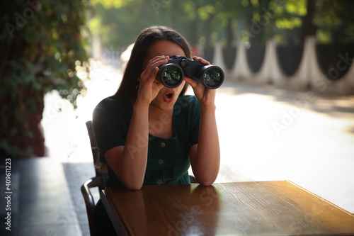 Obraz na plátně Jealous woman with binoculars spying on ex boyfriend in outdoor cafe