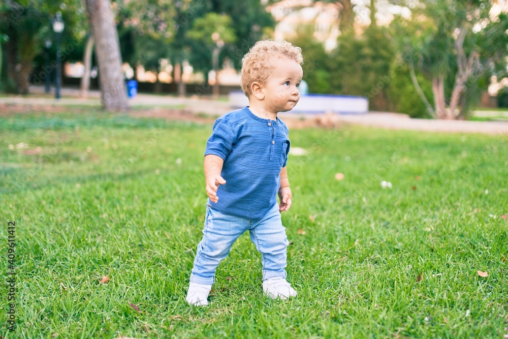 Cute and happy little boy having fun at the park on a sunny day. Beautiful blonde hair male toddler playing outdoors Cute and happy little boy having fun at the park on a sunny day. Beautiful blonde hair male toddler playing outdoors