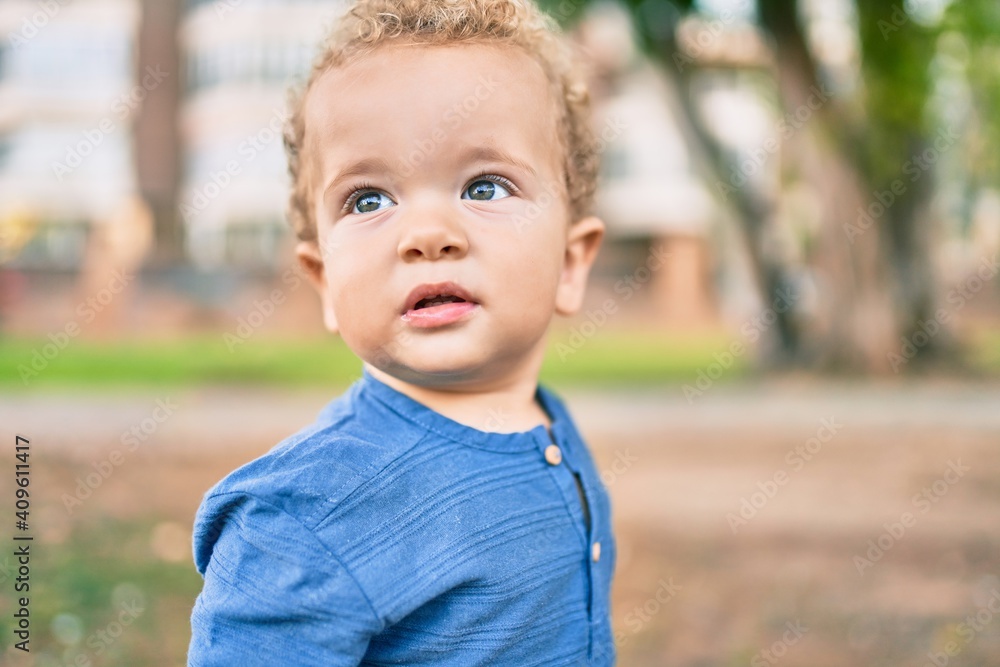 Cute and happy little boy having fun at the park on a sunny day. Beautiful blonde hair male toddler playing outdoors Cute and happy little boy having fun at the park on a sunny day. Beautiful blonde hair male toddler playing outdoors