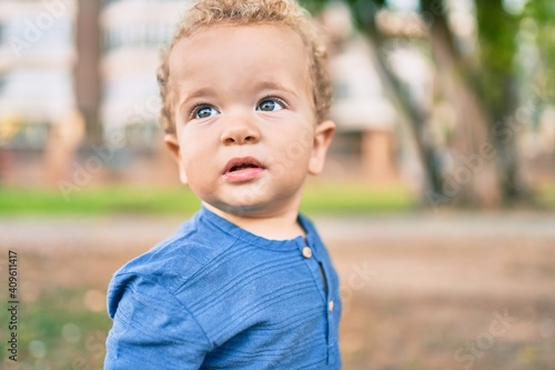 Cute and happy little boy having fun at the park on a sunny day. Beautiful blonde hair male toddler playing outdoors © Krakenimages.com