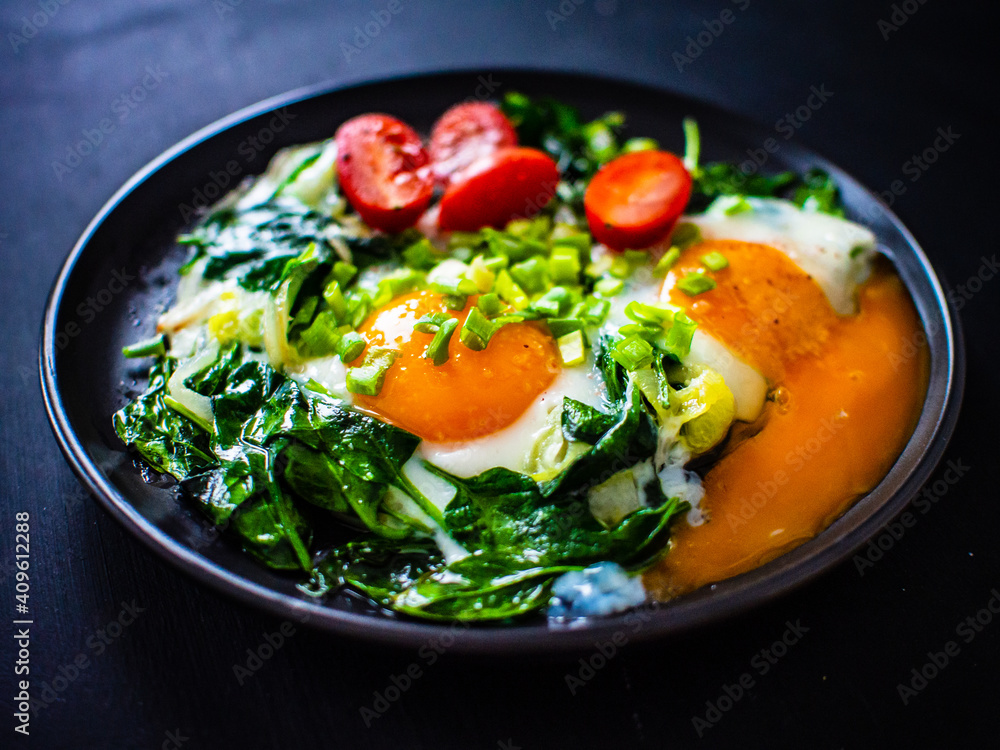 Sunny side up eggs with spinach on wooden table