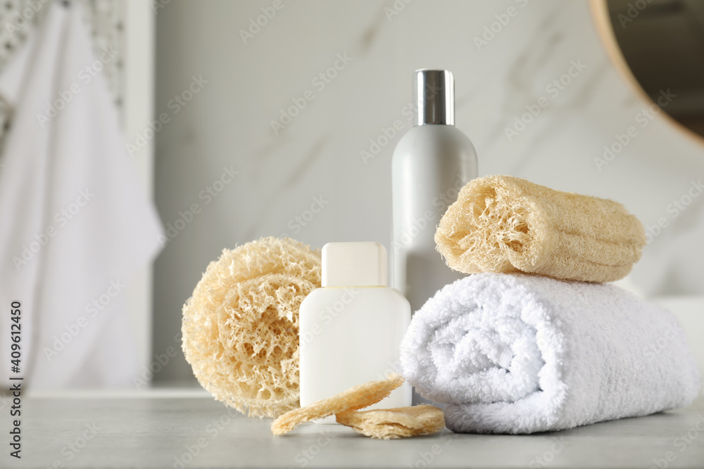 Natural loofah sponges, towel and cosmetic products on table in bathroom Natural loofah sponges, towel and cosmetic products on table in bathroom