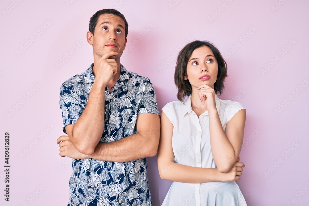 Beautiful couple wearing casual clothes with hand on chin thinking about question, pensive expression. smiling with thoughtful face. doubt concept. Beautiful couple wearing casual clothes with hand on chin thinking about question, pensive expression. smiling with thoughtful face. doubt concept.