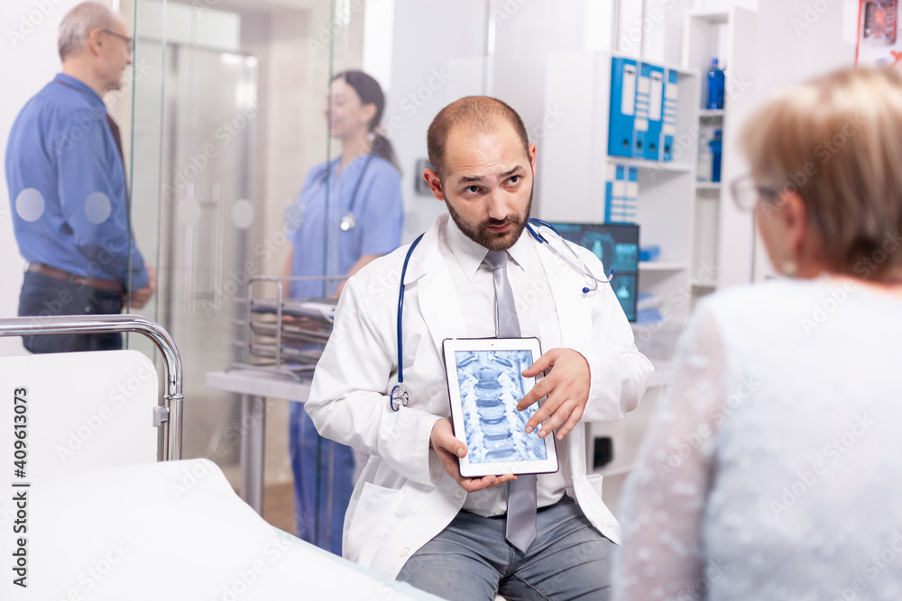 Obraz premium Doctor discussing about bones disease with senior woman during medical examination in hospital. Medical therapist showing and talking about x-ray with patient during consultation.