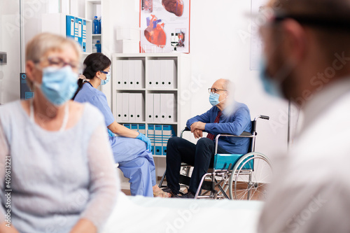 Handicapped patient wearing face mask as safety precaution in the course of consultation. Global health crisis, medical system during coronavirus pandemic, sick elderly patient in private clinic.