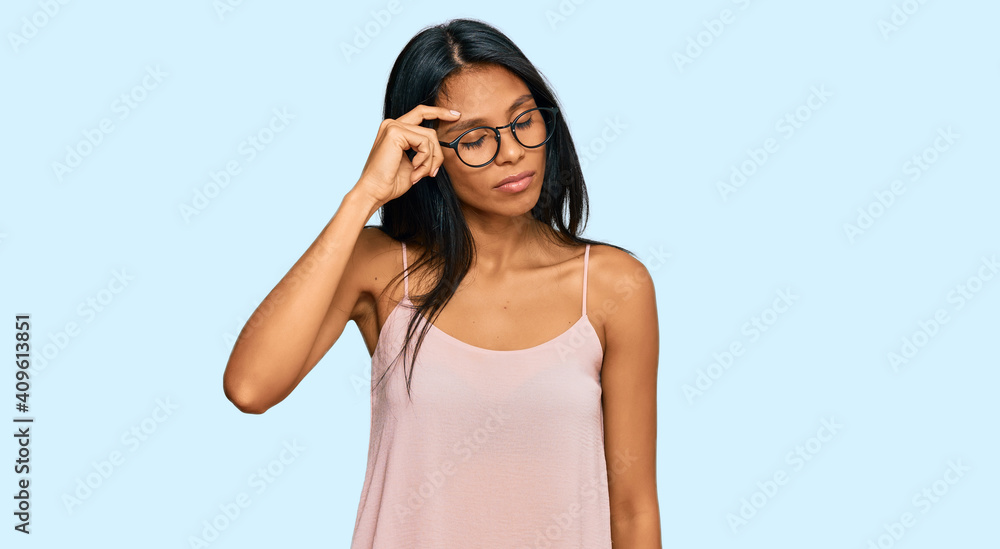 Young african american woman wearing casual clothes and glasses pointing unhappy to pimple on forehead, ugly infection of blackhead. acne and skin problem