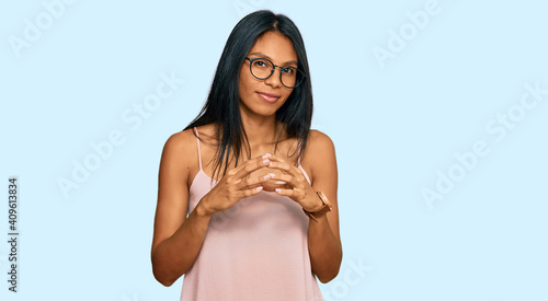 Young african american woman wearing casual clothes and glasses hands together and fingers crossed smiling relaxed and cheerful. success and optimistic