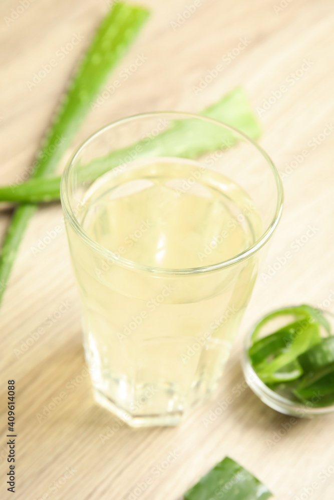 Fresh aloe drink in glass and leaves on wooden table Fresh aloe drink in glass and leaves on wooden table