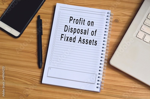 Profit on disposal of fixed assets label on notepad with laptop and smartphone