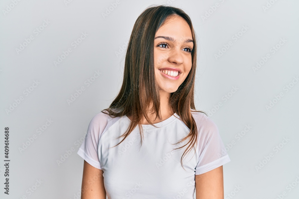 Young brunette woman wearing casual white t shirt looking to side, relax profile pose with natural face and confident smile. Young brunette woman wearing casual white t shirt looking to side, relax profile pose with natural face and confident smile.