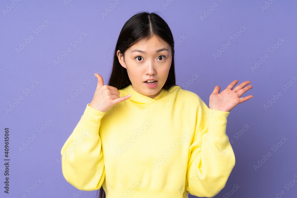 Young asian woman isolated on purple background making phone gesture and doubting Young asian woman isolated on purple background making phone gesture and doubting