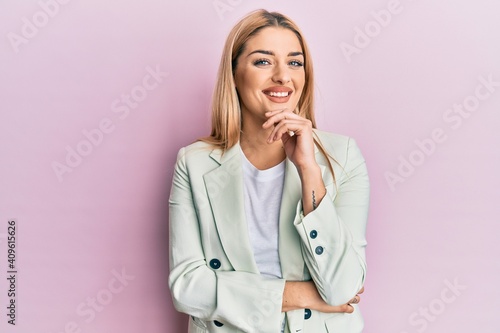 Young caucasian woman wearing business clothes smiling looking confident at the camera with crossed arms and hand on chin. thinking positive.