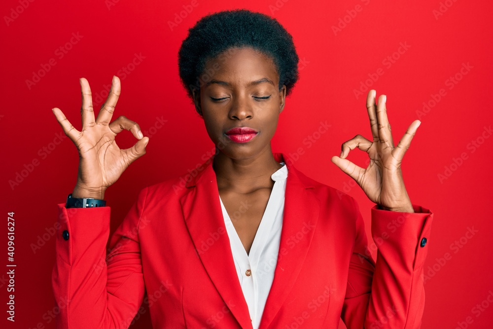 Young african american girl wearing business clothes relax and smiling with eyes closed doing meditation gesture with fingers. yoga concept. Young african american girl wearing business clothes relax and smiling with eyes closed doing meditation gesture with fingers. yoga concept.