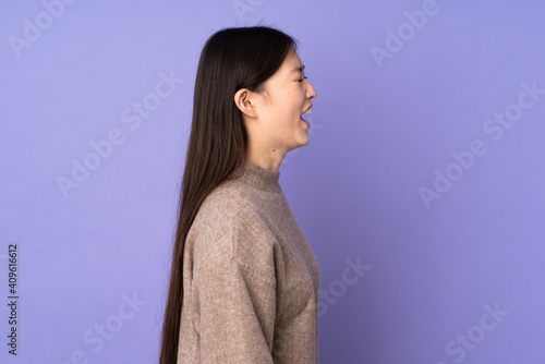 Young asian woman isolated on purple background laughing in lateral position © luismolinero