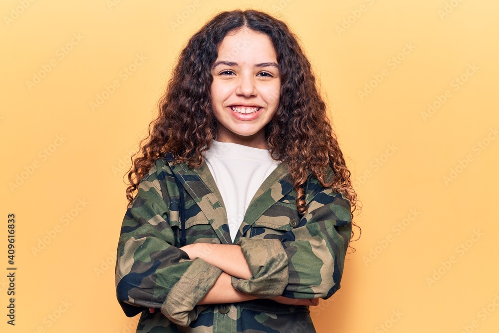Beautiful kid girl with curly hair wearing camouflage jacket happy face smiling with crossed arms looking at the camera. positive person. Beautiful kid girl with curly hair wearing camouflage jacket happy face smiling with crossed arms looking at the camera. positive person.