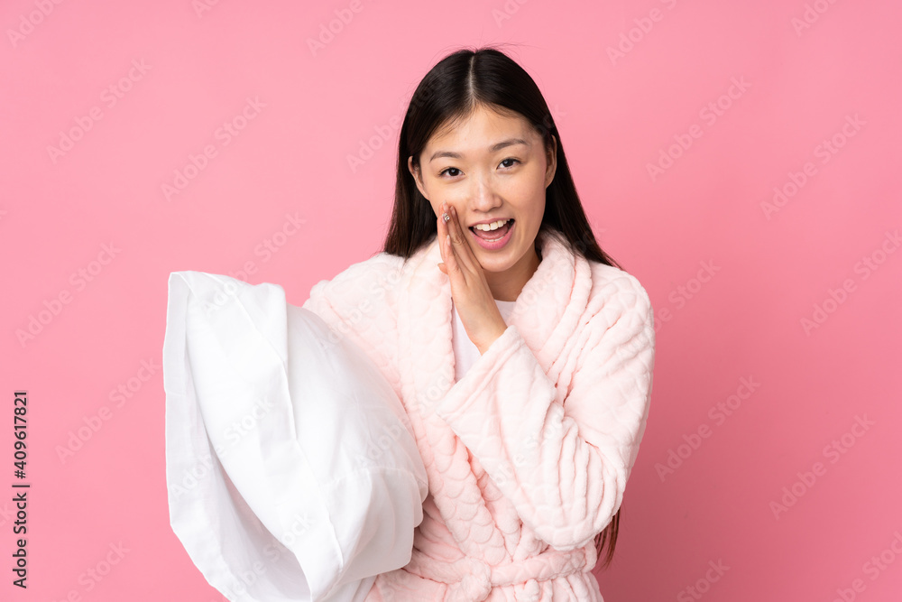Young Asian woman in pajamas isolated on pink background whispering something Young Asian woman in pajamas isolated on pink background whispering something