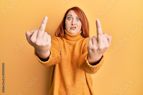 Quadro su tela Beautiful redhead woman showing middle finger doing bad gesture in shock face, l