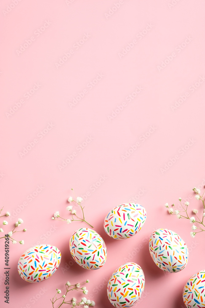 Happy Easter concept. Flat lay Easter eggs on pastel pink background with flowers. Top view with copy space.
