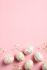 Happy Easter concept. Flat lay Easter eggs on pastel pink background with flowers. Top view with copy space.