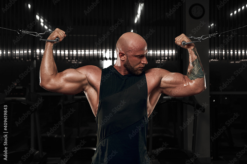 Bodybuilder male model training biceps muscles with dumbbell. model in black shirt Bodybuilder male model training biceps muscles with dumbbell. model in black shirt