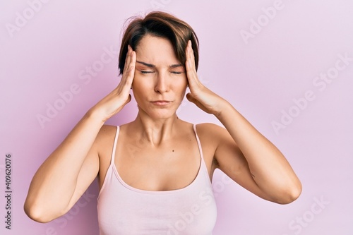 Fotografie Young brunette woman with short hair over pink background suffering from headache desperate and stressed because pain and migraine