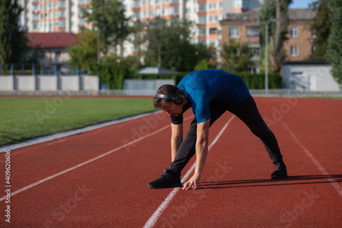 Sportive guy doing stretching and listening music