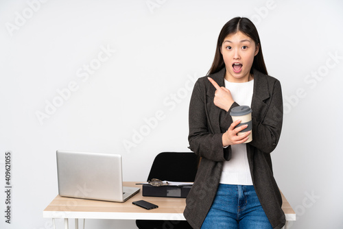 Business asian woman in her workplace isolated on white background surprised and pointing side