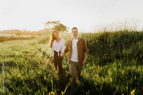 Beautiful young woman and a man walk, hug and kiss in nature at sunset.