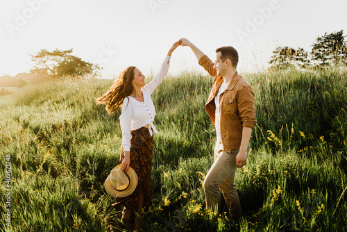 Beautiful young woman and a man walk, hug and kiss in nature at sunset.