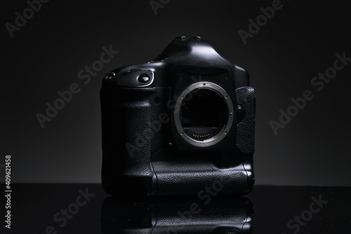 The massive carcass of a professional SLR camera without a lens stands on a black background. Advertising photo of an outdated camera model. Front view