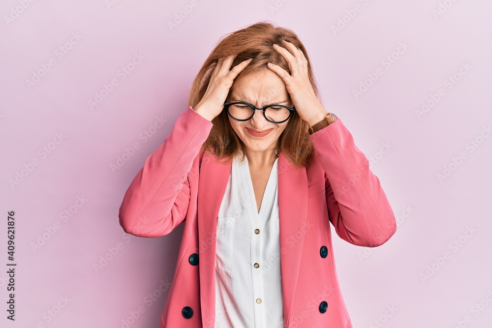 Young caucasian woman wearing business style and glasses suffering from headache desperate and stressed because pain and migraine. hands on head. Young caucasian woman wearing business style and glasses suffering from headache desperate and stressed because pain and migraine. hands on head.