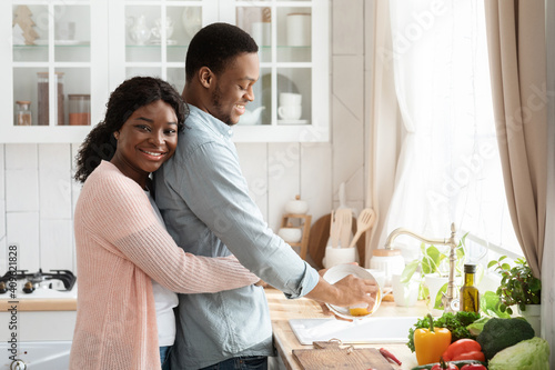 Fotografie Loving Black Husband Helping With Cleaning, Washing Dishes After Lunch In Kitche