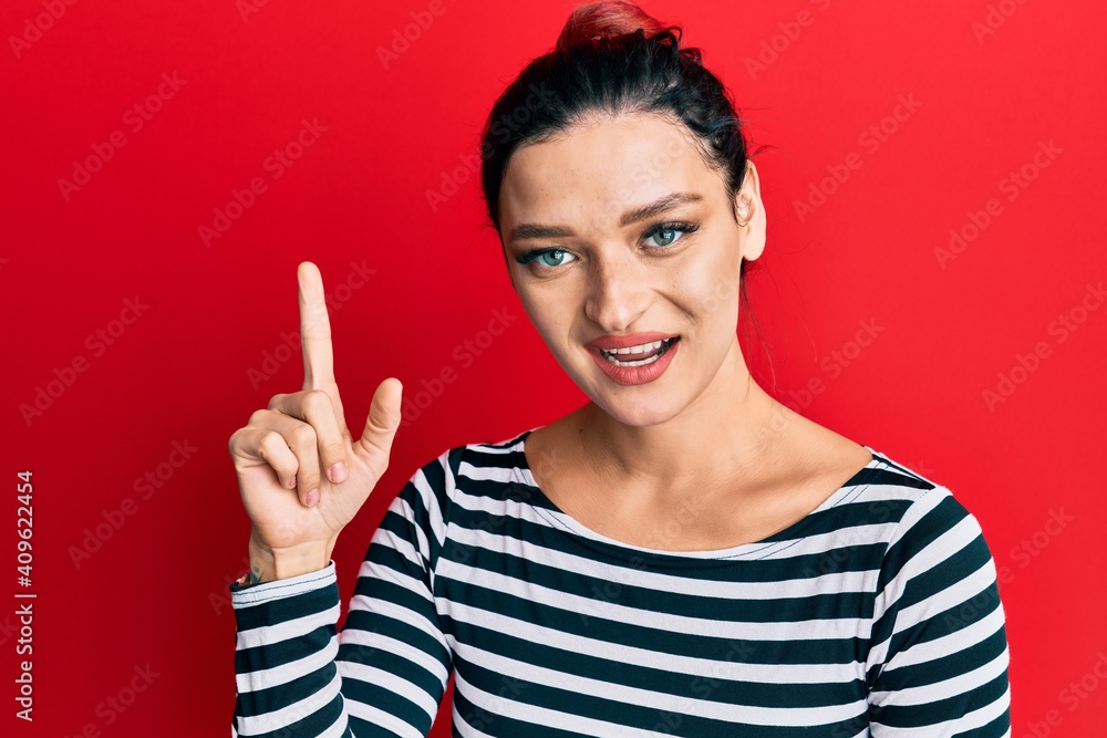 Young caucasian woman wearing casual clothes smiling with an idea or question pointing finger up with happy face, number one Young caucasian woman wearing casual clothes smiling with an idea or question pointing finger up with happy face, number one