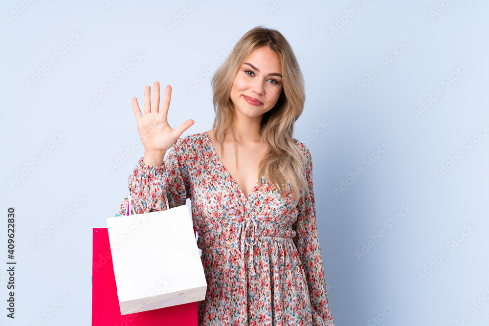 Teenager Russian girl with shopping bag isolated on blue background counting five with fingers Teenager Russian girl with shopping bag isolated on blue background counting five with fingers