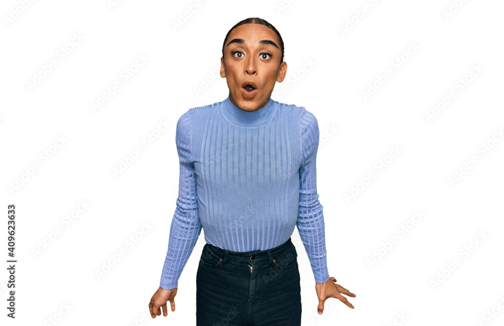 Fototapeta premium Hispanic transgender man wearing make up and long hair wearing casual clothes scared and amazed with open mouth for surprise, disbelief face