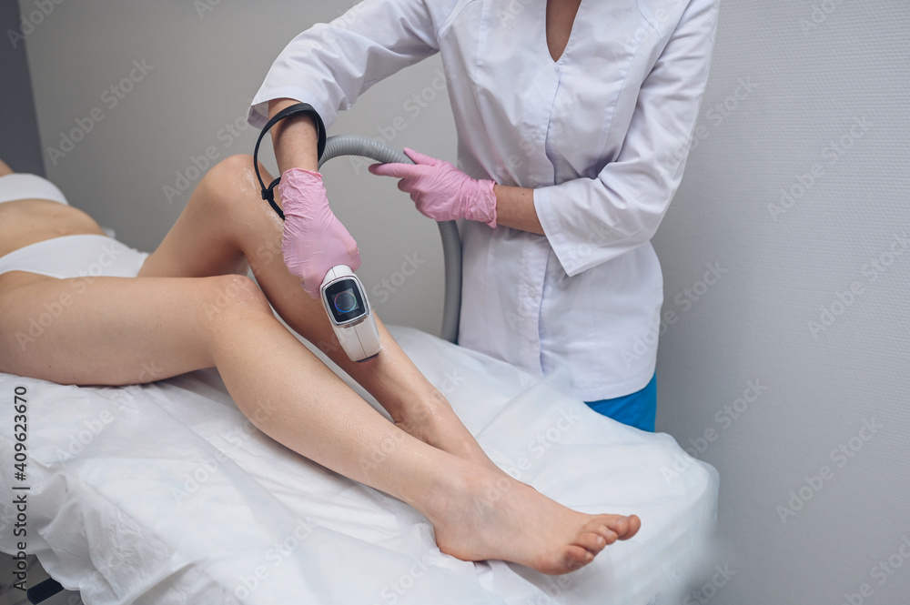 Laser epilation and cosmetology in beauty salon. Hair removal procedure. Laser epilation, cosmetology, spa, and hair removal concept. Beautiful blonde woman getting hair removing on legs. Laser epilation and cosmetology in beauty salon. Hair removal procedure. Laser epilation, cosmetology, spa, and hair removal concept. Beautiful blonde woman getting hair removing on legs.
