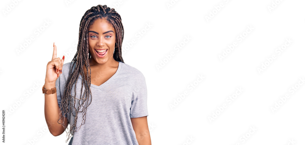 Young african american woman with braids wearing casual clothes pointing finger up with successful idea. exited and happy. number one. Young african american woman with braids wearing casual clothes pointing finger up with successful idea. exited and happy. number one.