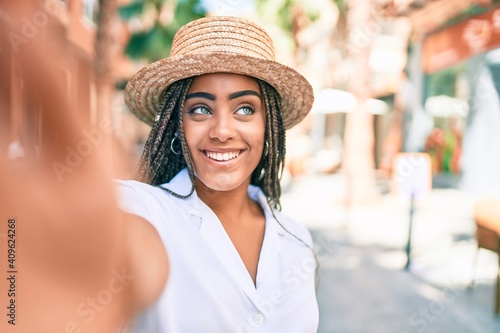 Young african american woman with braids smiling happy taking selfie picture outdoors on a sunny day of summer © Krakenimages.com