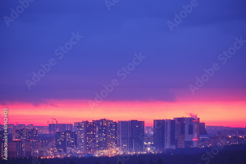 Illuminated windows of the night city house and roads with cars. Pink evening sunset over modern Moscow  Russia. Top view of the city at dusk