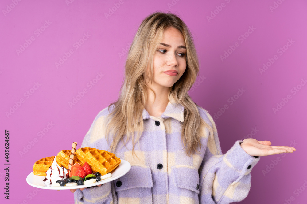 Teenager Russian girl holding waffles isolated on purple background holding copyspace with doubts Teenager Russian girl holding waffles isolated on purple background holding copyspace with doubts