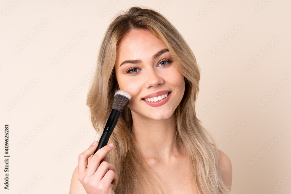 Teenager blonde girl with makeup brush over isolated background Teenager blonde girl with makeup brush over isolated background