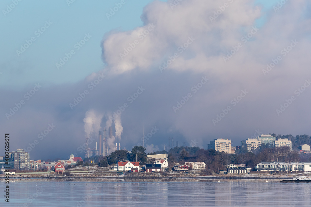Magenta clouds and heavy industry billowing smoke and vapor on a cold winter day on Swedens west coast