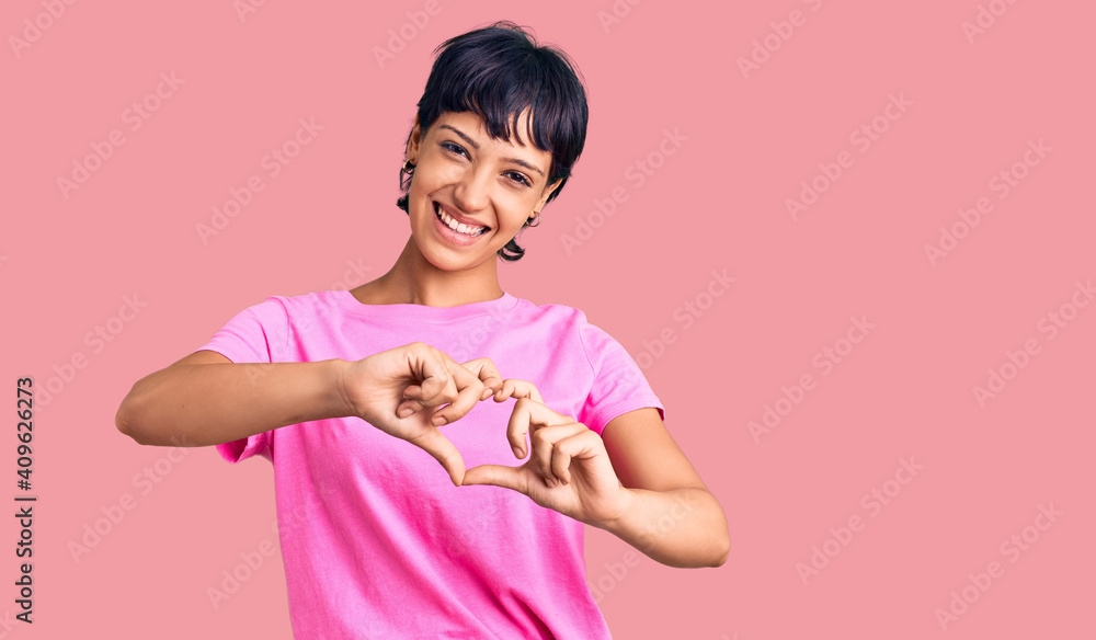 Young brunette woman with short hair wearing casual clothes smiling in love doing heart symbol shape with hands. romantic concept. Young brunette woman with short hair wearing casual clothes smiling in love doing heart symbol shape with hands. romantic concept.