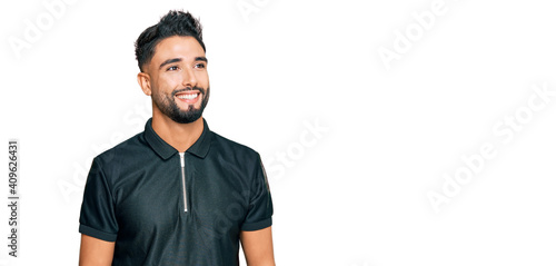 Young man with beard wearing sportswear looking away to side with smile on face, natural expression. laughing confident.