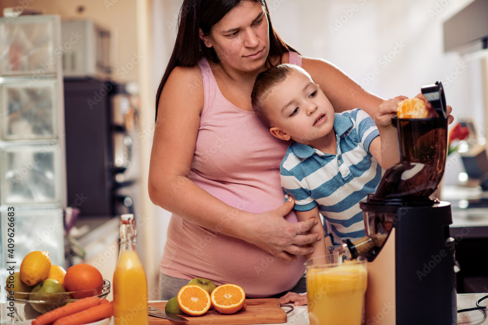 Pregnant mother with son making juice