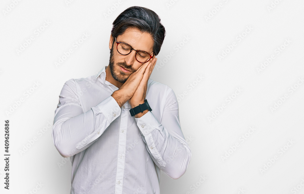 Young hispanic man wearing business shirt and glasses sleeping tired dreaming and posing with hands together while smiling with closed eyes. Young hispanic man wearing business shirt and glasses sleeping tired dreaming and posing with hands together while smiling with closed eyes.