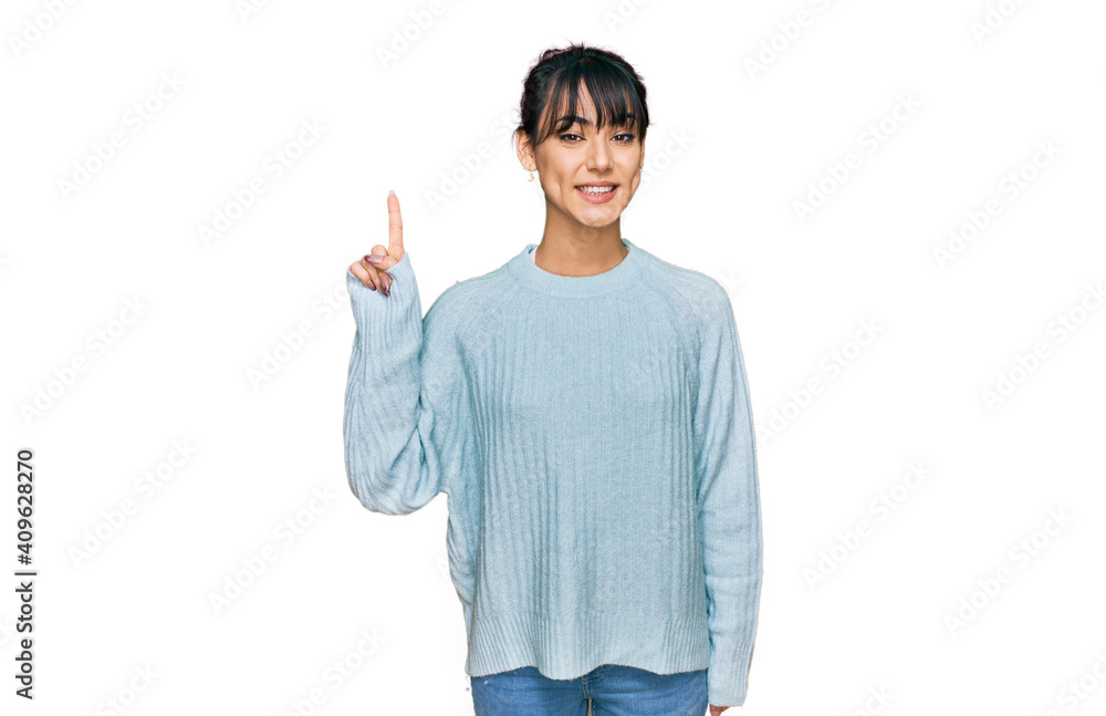 Young hispanic woman wearing casual clothes showing and pointing up with finger number one while smiling confident and happy. Young hispanic woman wearing casual clothes showing and pointing up with finger number one while smiling confident and happy.