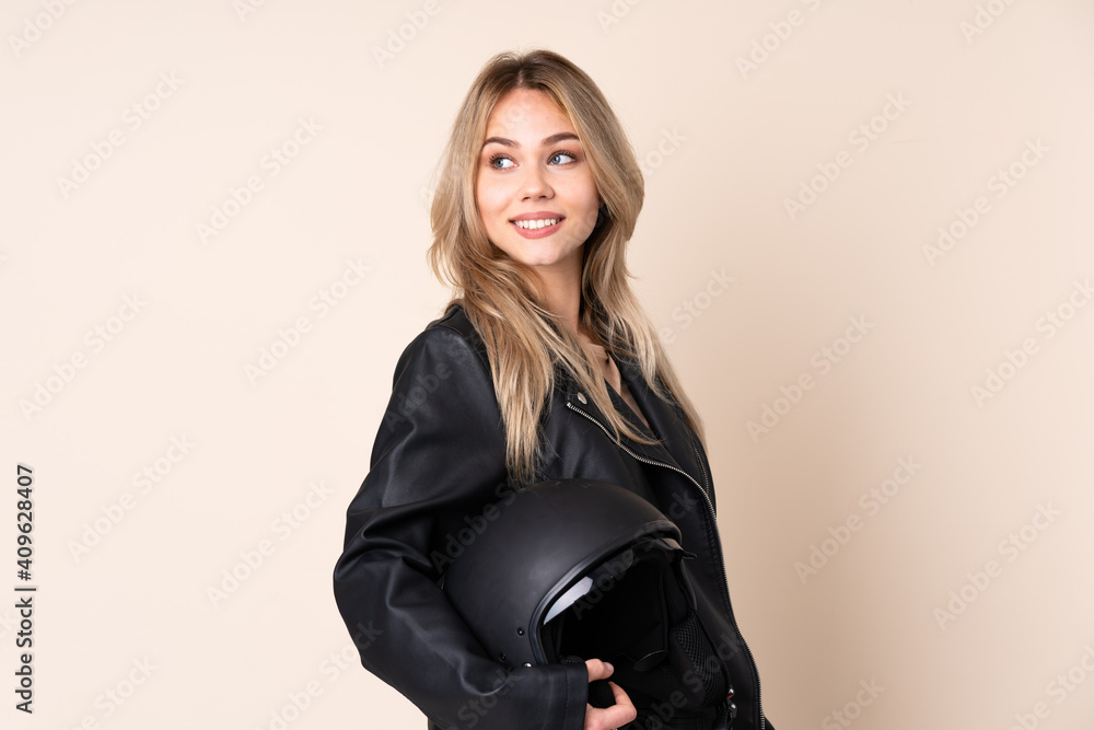 Russian girl with a motorcycle helmet isolated on beige background with arms crossed and happy Russian girl with a motorcycle helmet isolated on beige background with arms crossed and happy