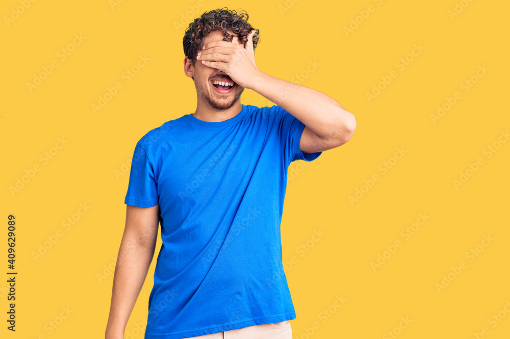 © Krakenimages.com - Young handsome man with curly hair wearing casual clothes smiling and laughing with hand on face covering eyes for surprise. blind concept. © Krakenimages.com - Young handsome man with curly hair wearing casual clothes smiling and laughing with hand on face covering eyes for surprise. blind concept.