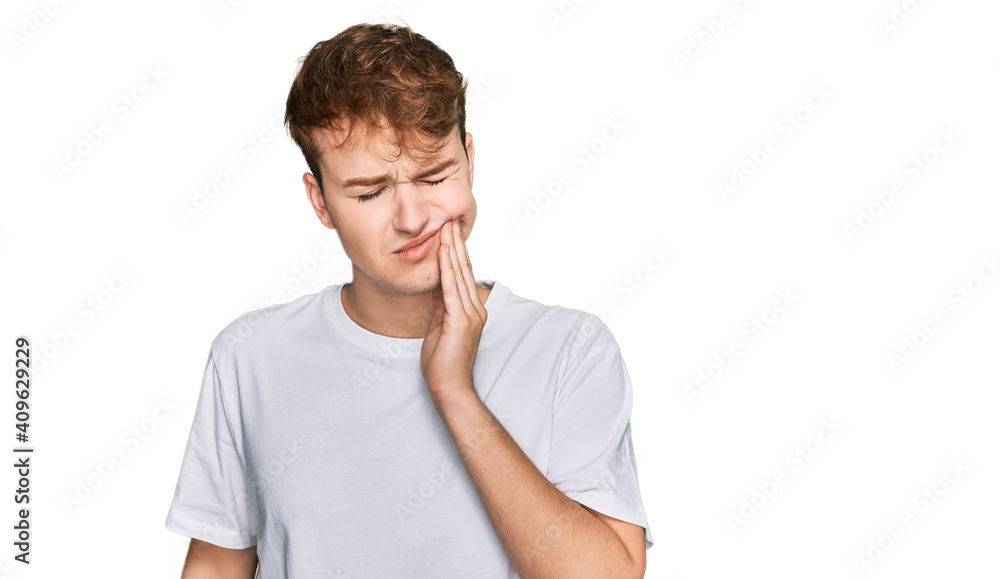 Young caucasian man wearing casual white t shirt touching mouth with hand with painful expression because of toothache or dental illness on teeth. dentist Young caucasian man wearing casual white t shirt touching mouth with hand with painful expression because of toothache or dental illness on teeth. dentist